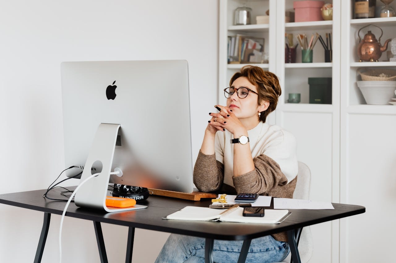 A woman is thinking in front of the computer