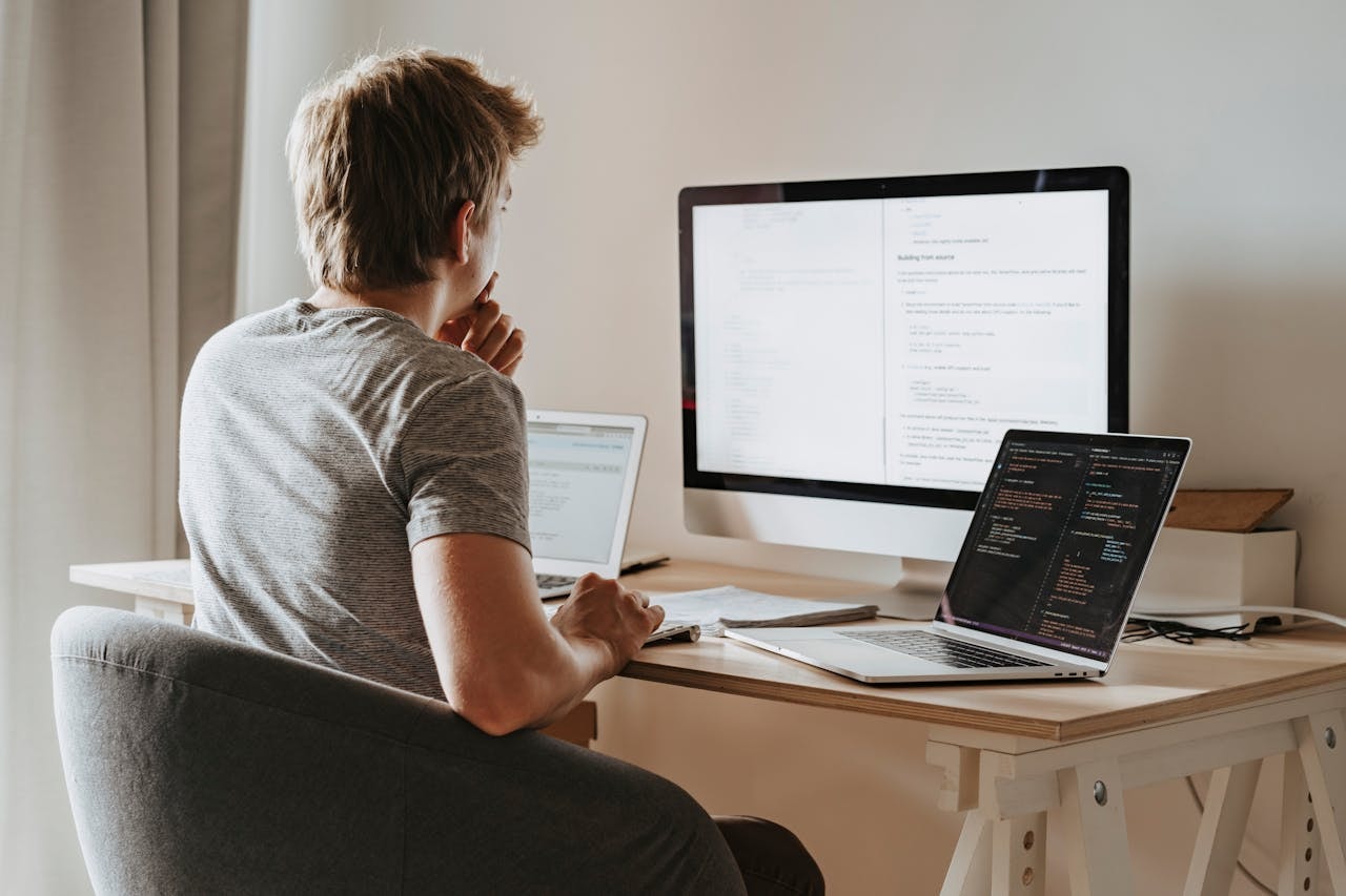 A man in front of computers doing coding