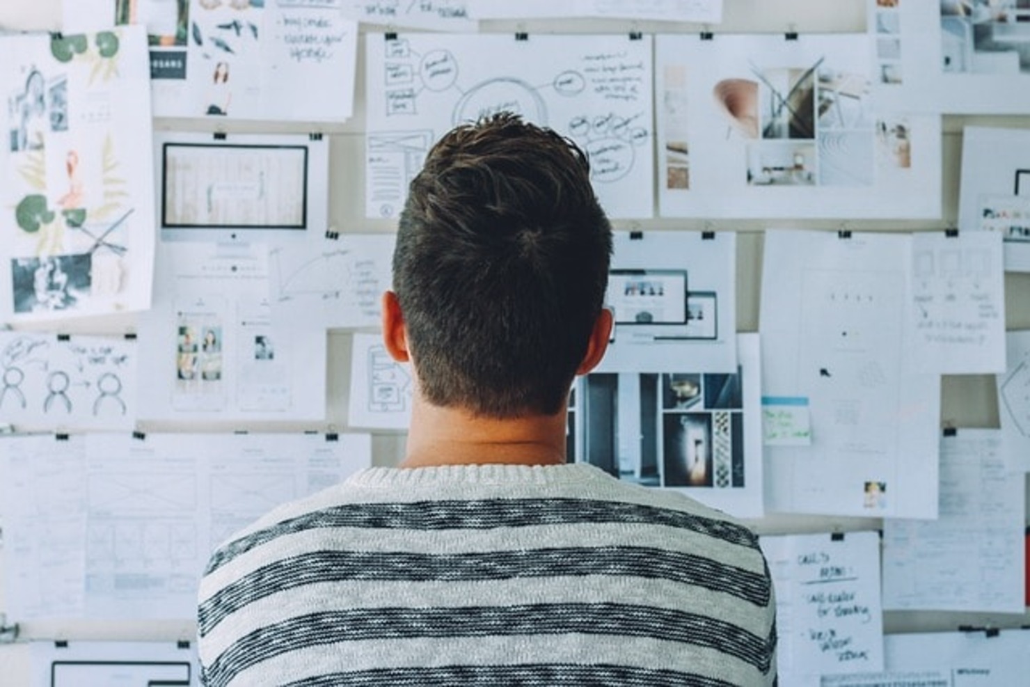 A man is looking at a drawing board full of papers