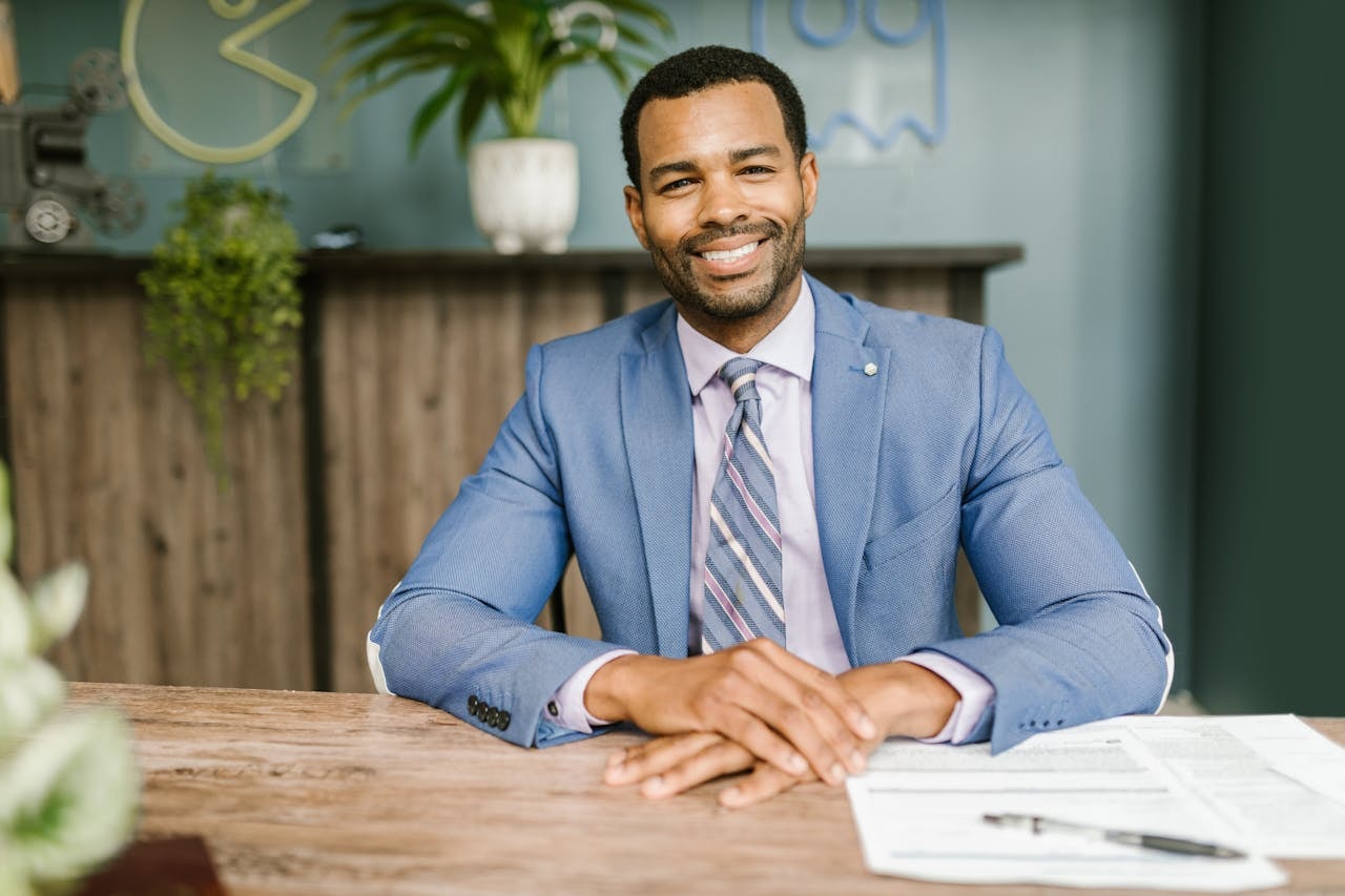 A smiling man in a blue suit sitting by the table
