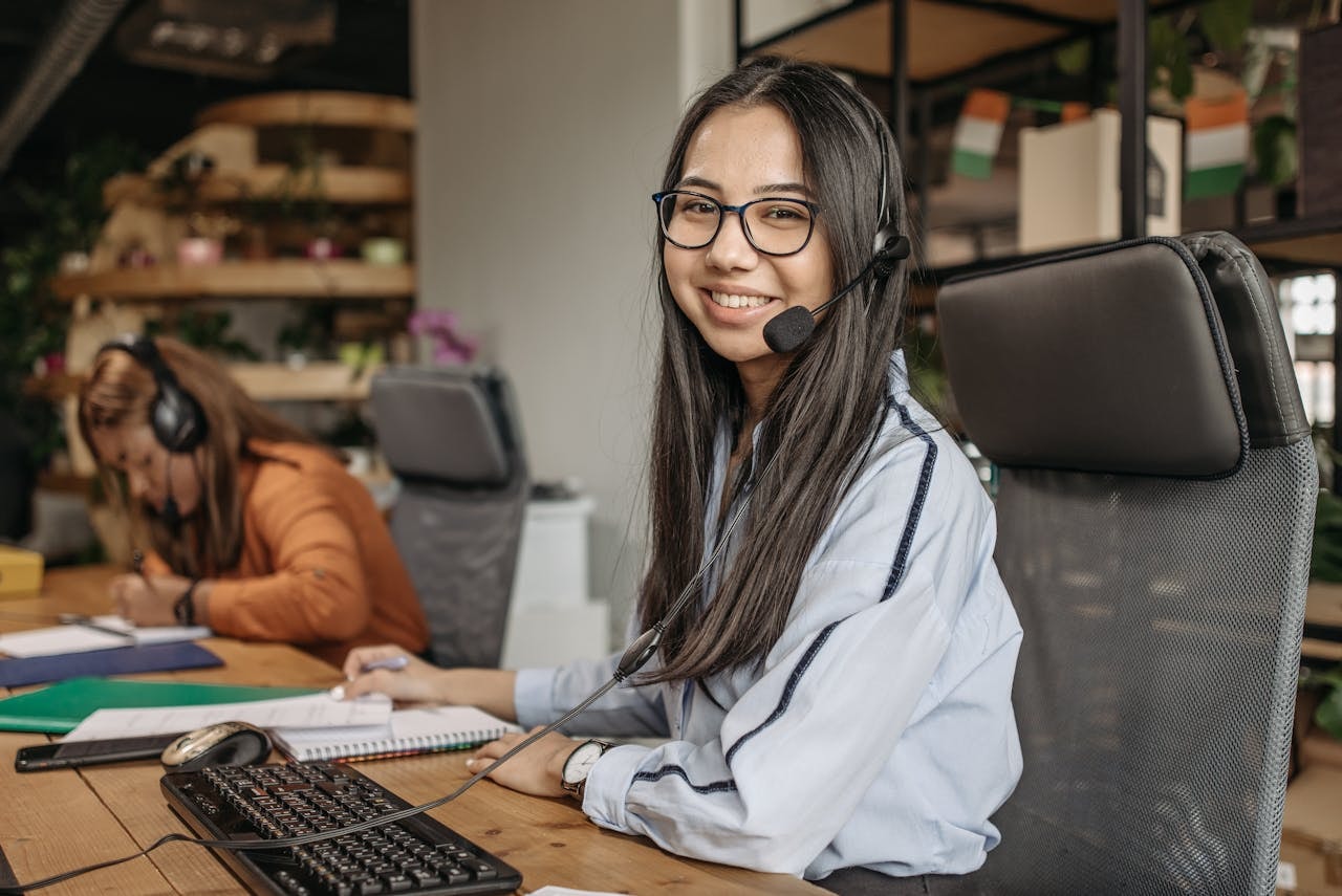 A woman wearing a headset and sitting on her workspace