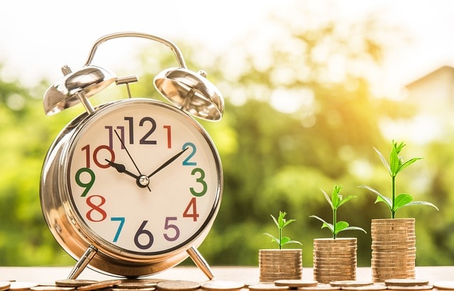 An old clock next to coins
