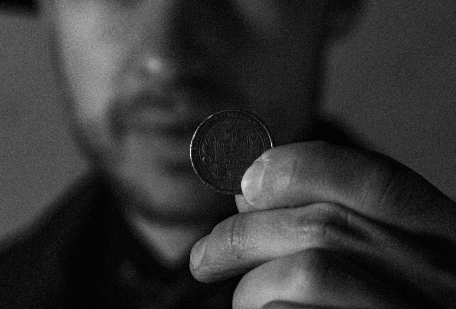 Black and White Photo of a Man Holding a Coin in his Left Hand.