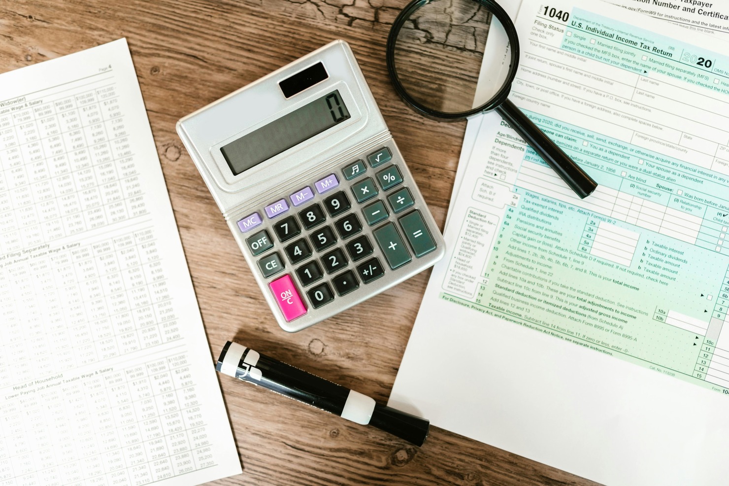 Gray Calculator and Black Magnifying Glass next to tax form.