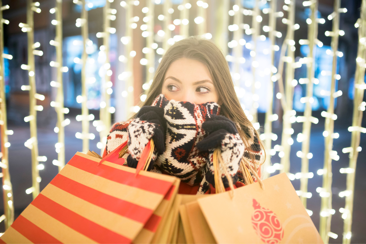 Lady with a bandana mask covering half her face, holding shopping bags.