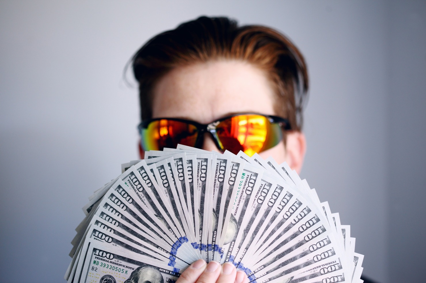Man with a fan of American one hundred dollar bills.
