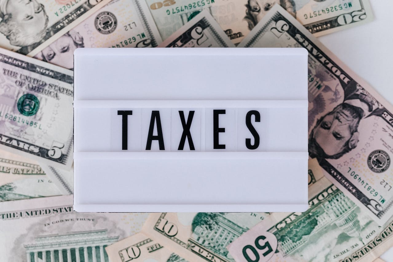 Mini board that displays the word TAXES and placed on top of American dollar bills