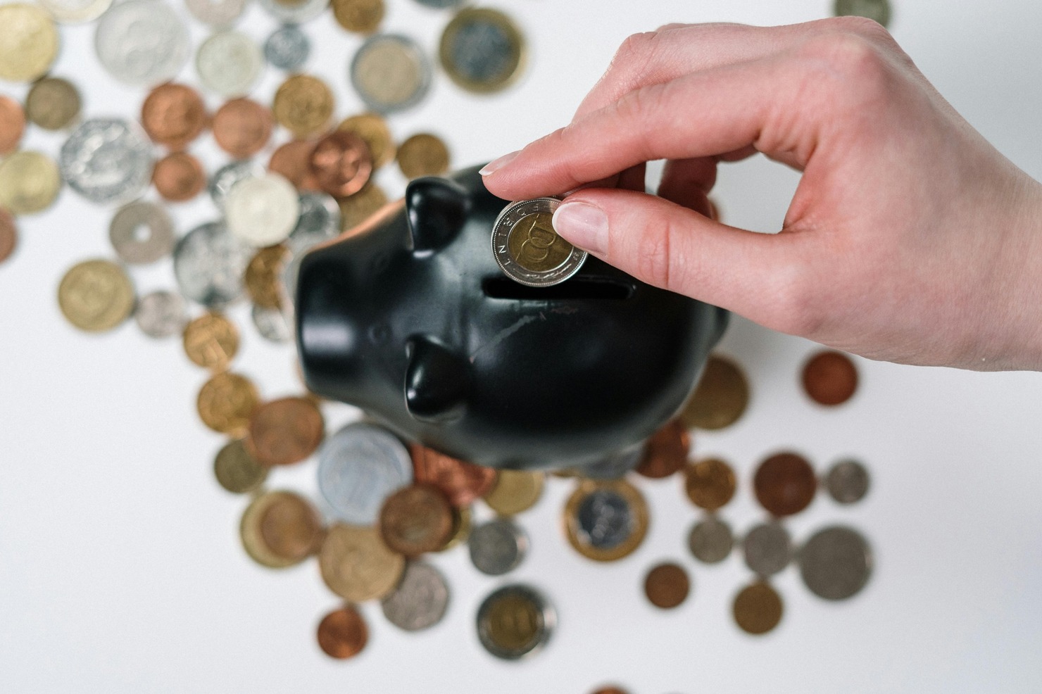 Person Putting Coin in a Piggy Bank.