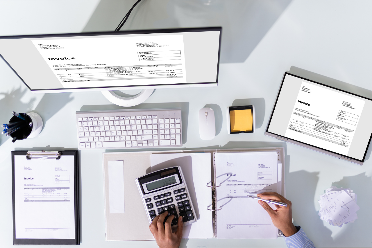 A chartered accountant working on invoices using tablet and computer.