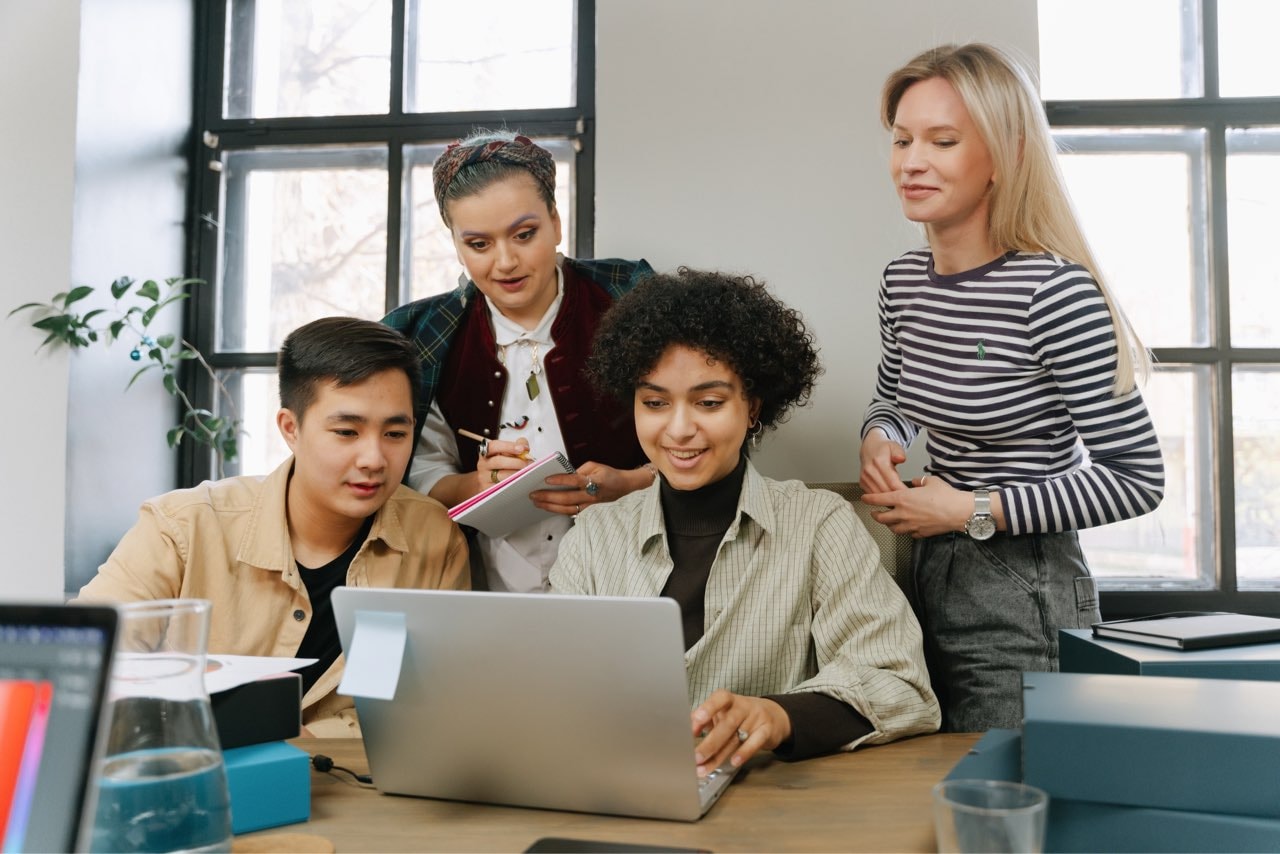 A group of people is looking at a laptop.