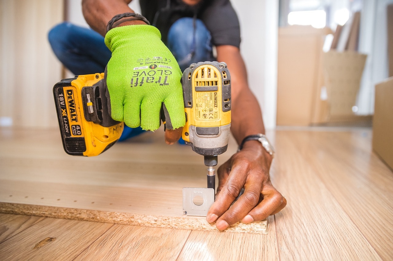 A handyman using a drilling tool on a piece of wood.