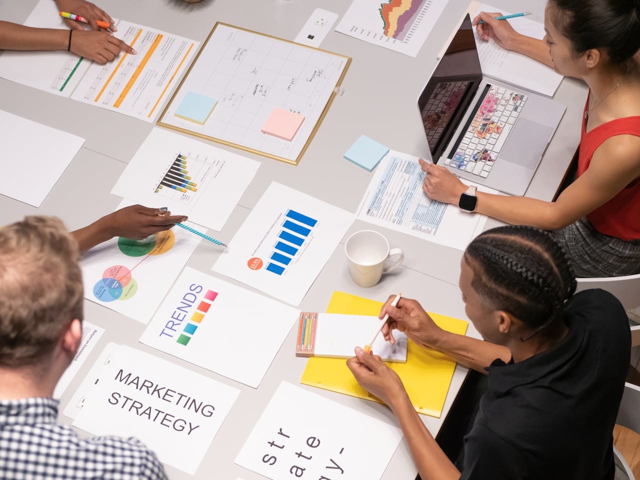 A high angle shot of people in a meeting with business materials scattered on the table