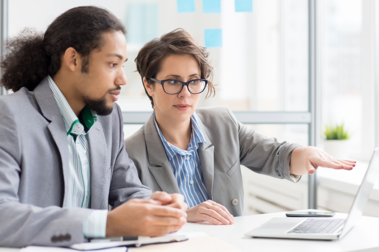 A man and woman are looking at data on a laptop.
