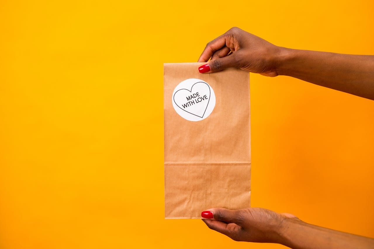 A person holding a paper bag with a sticker label Made with love