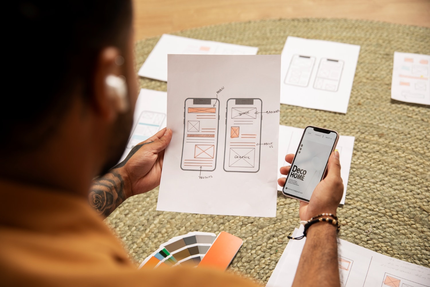 A person is looking at a cellphone screen while holding UX design paper