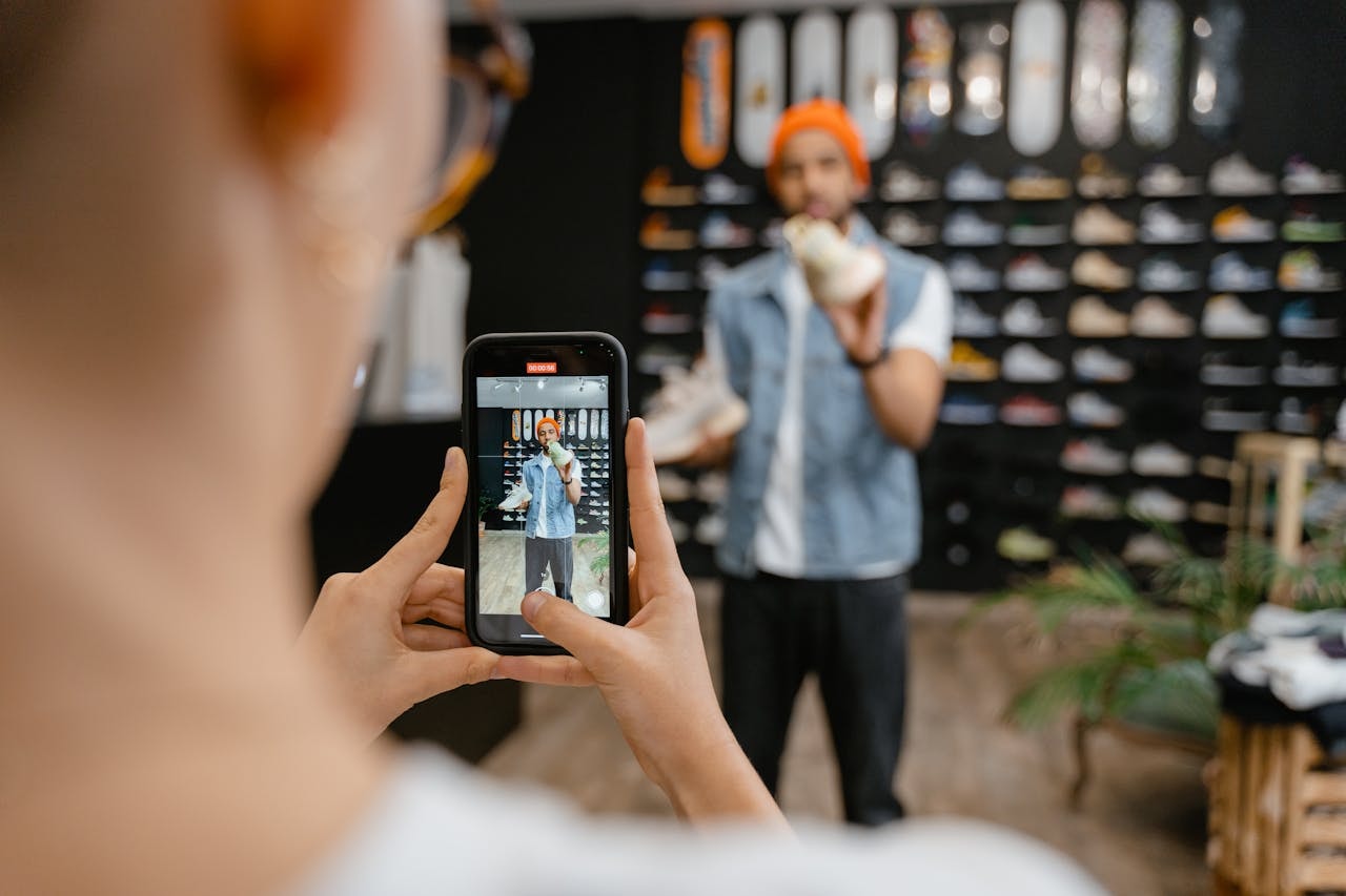 A person recording a a video of a man talking about a pair of shoes