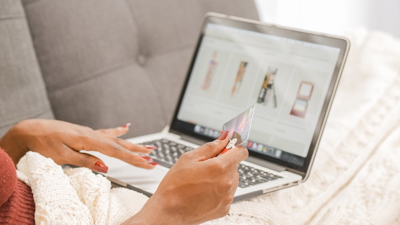 A woman browsing an online store with a credit card in her right hand