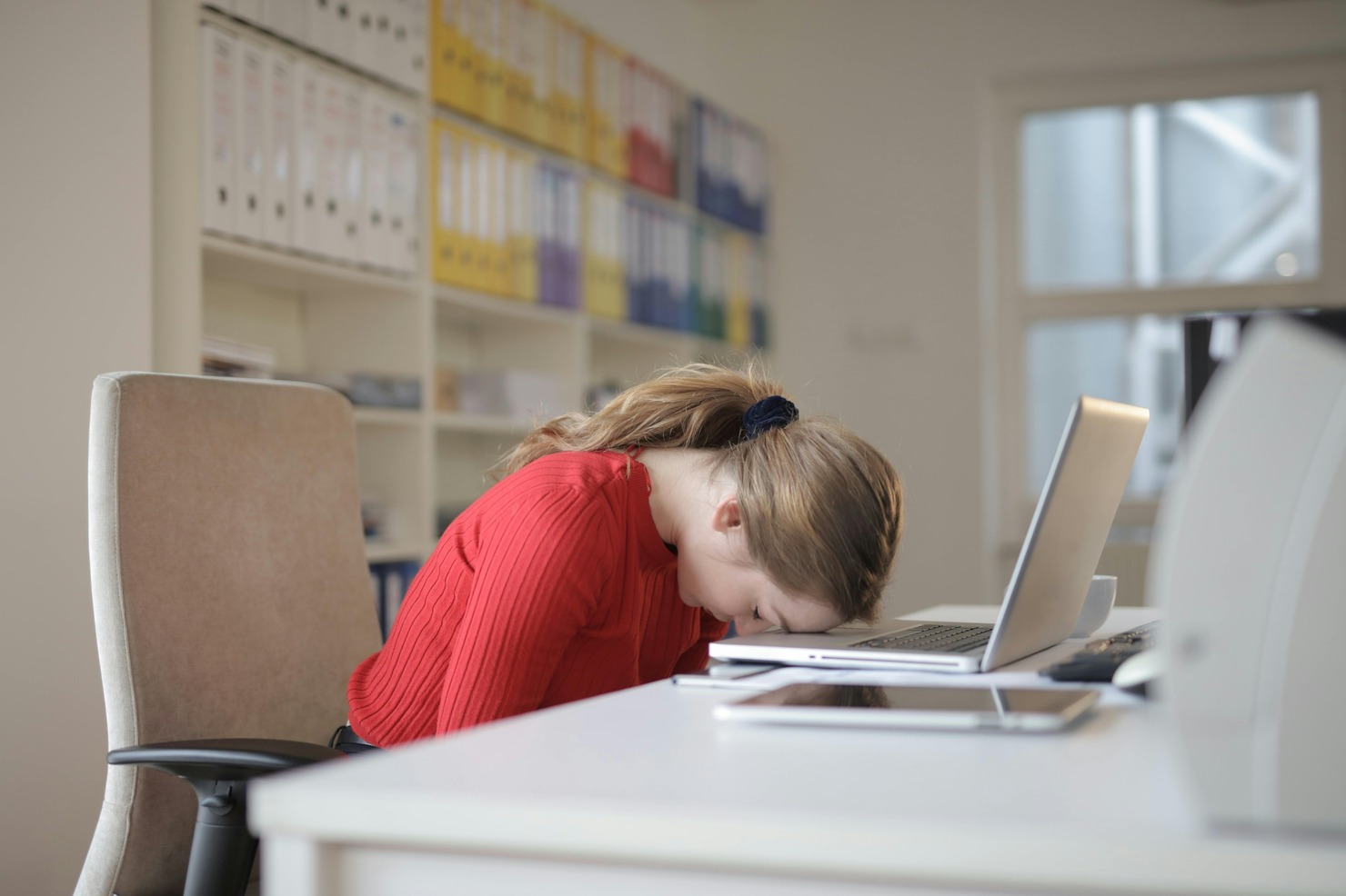 A woman looking burnt out and unmotivated in front of a laptop.