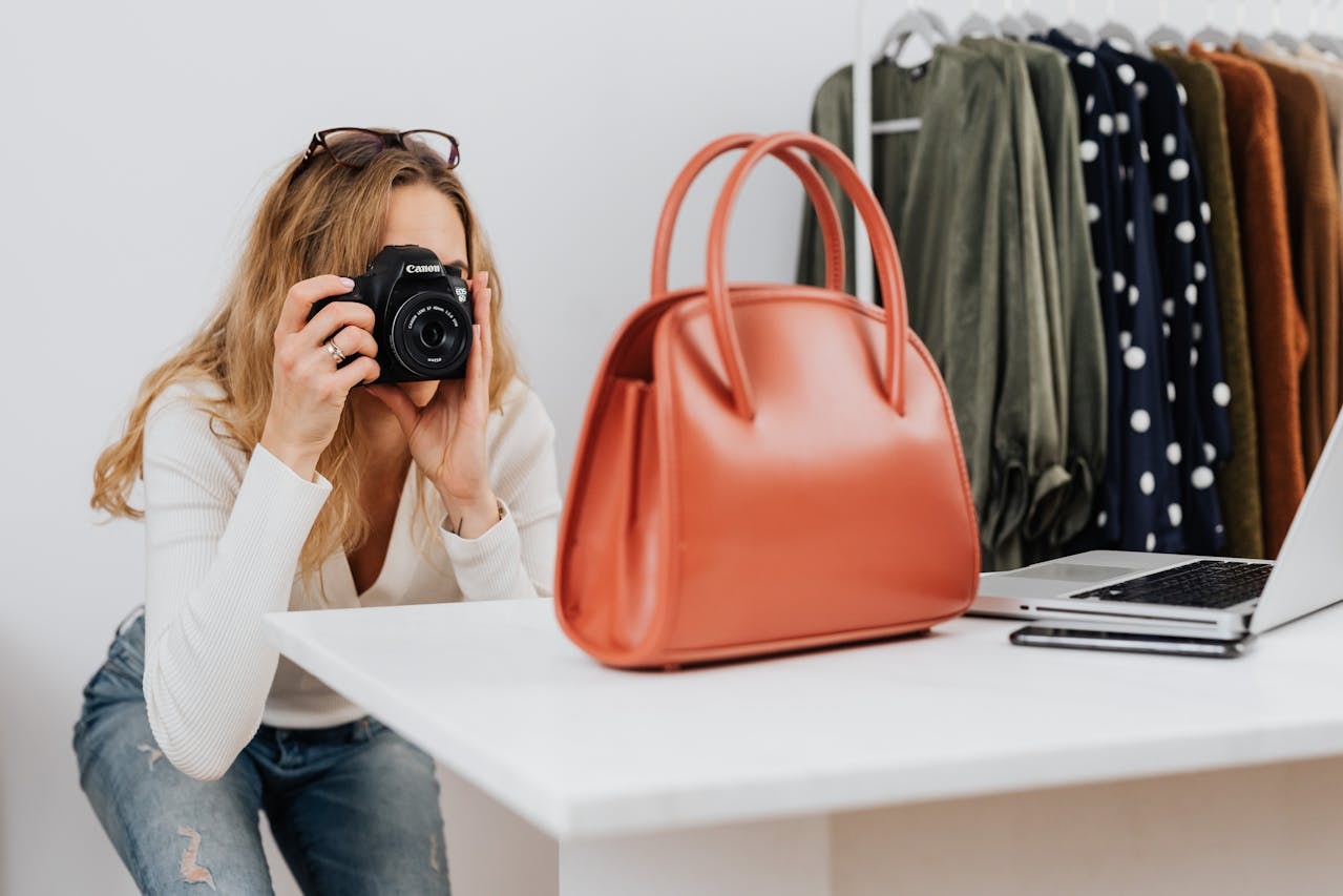 A woman taking a photo of a handbag using a black camera