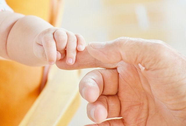 Adult hand holding baby hand.