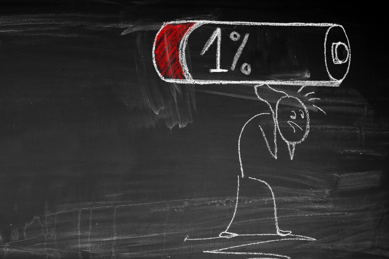 Blackboard drawing of a person carrying large almost drained battery.