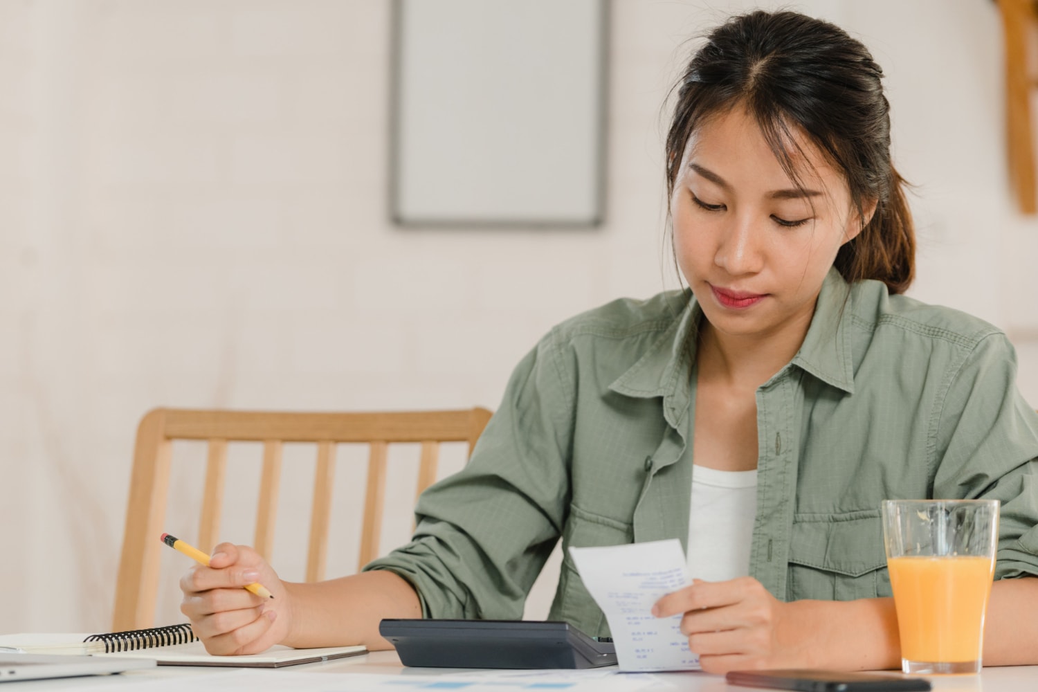 Business Asian women records income and expenses at home.