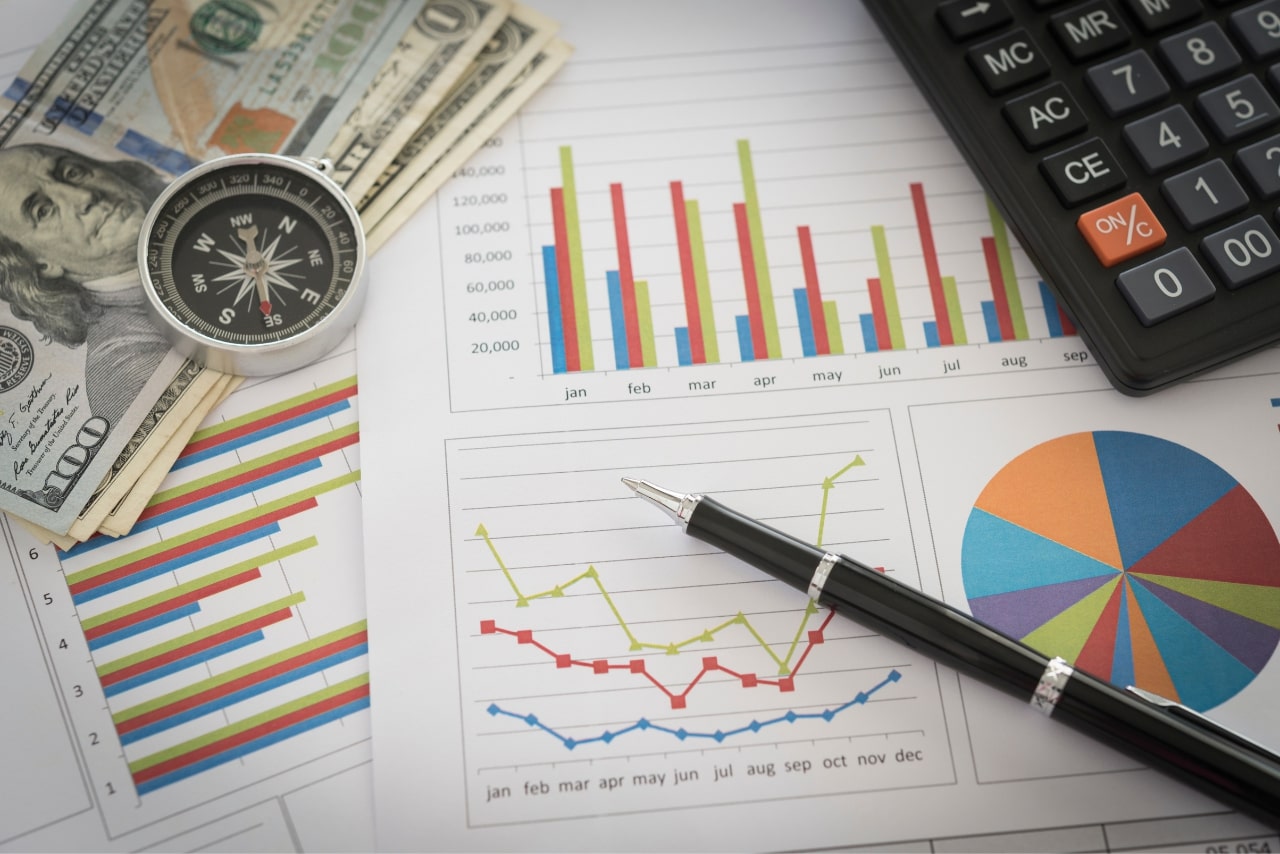 Cash, compass, pen, financing documents and calculator on desk.