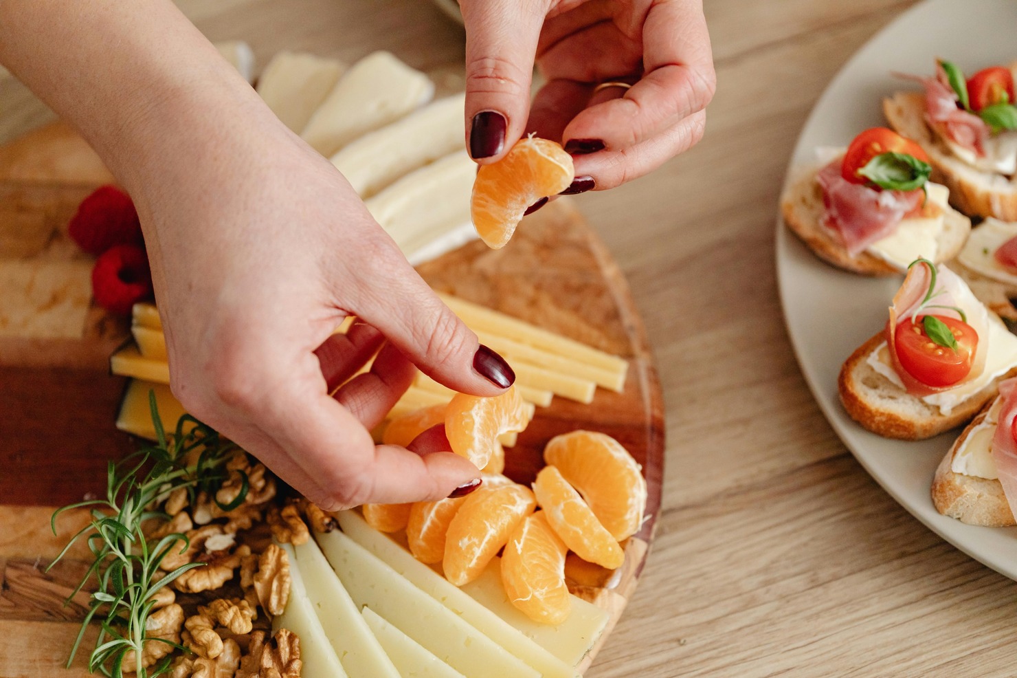 Close-Up Photo of a Person's Hands Preparing Oranges on a Board.