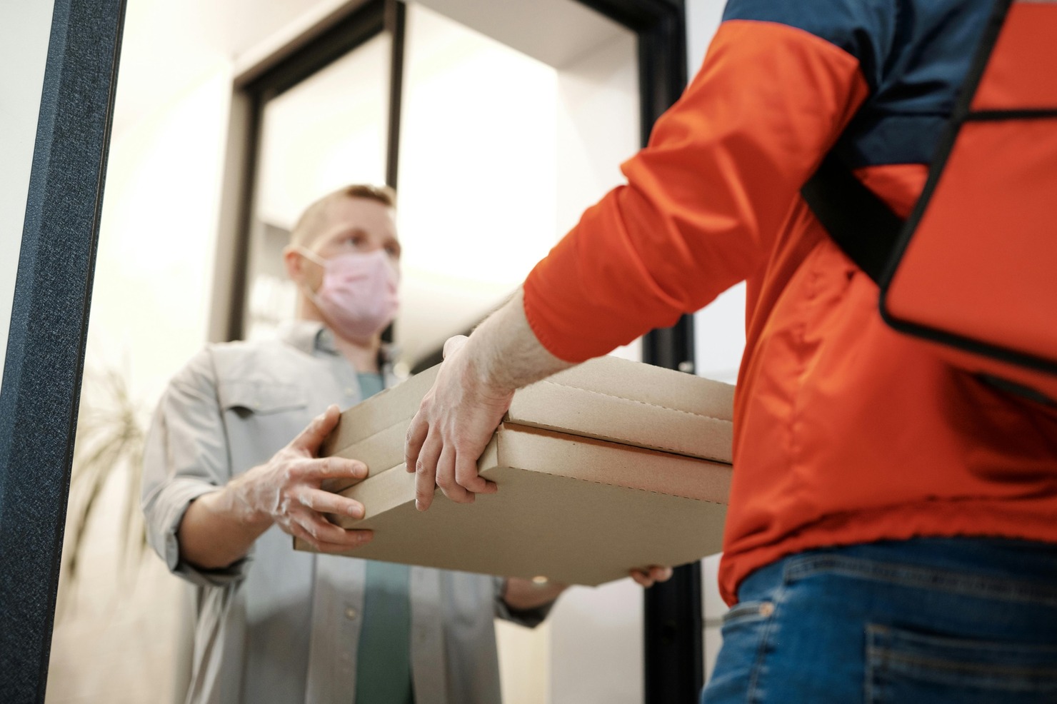Delivery person handing food order to customer.