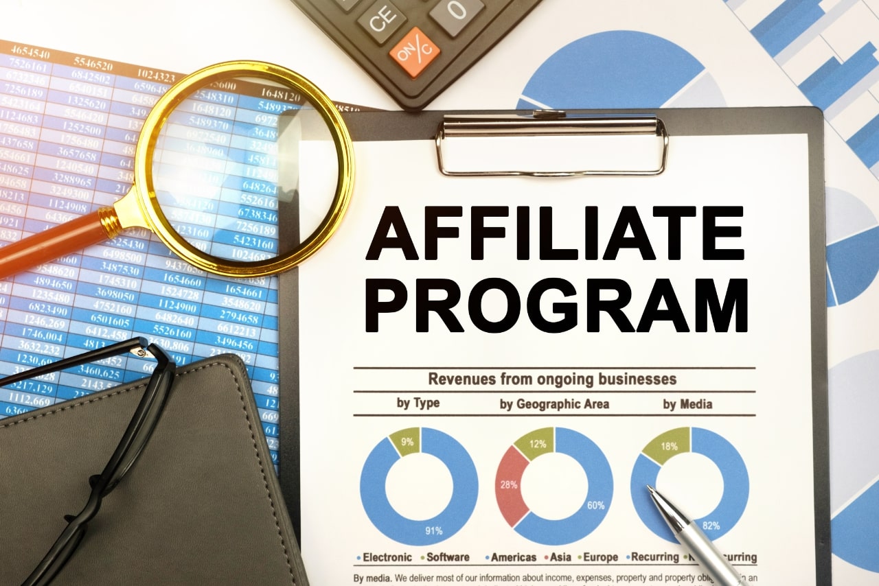 Desk has magnifying glass, reports, notebook and document with inscription Affiliate Program.