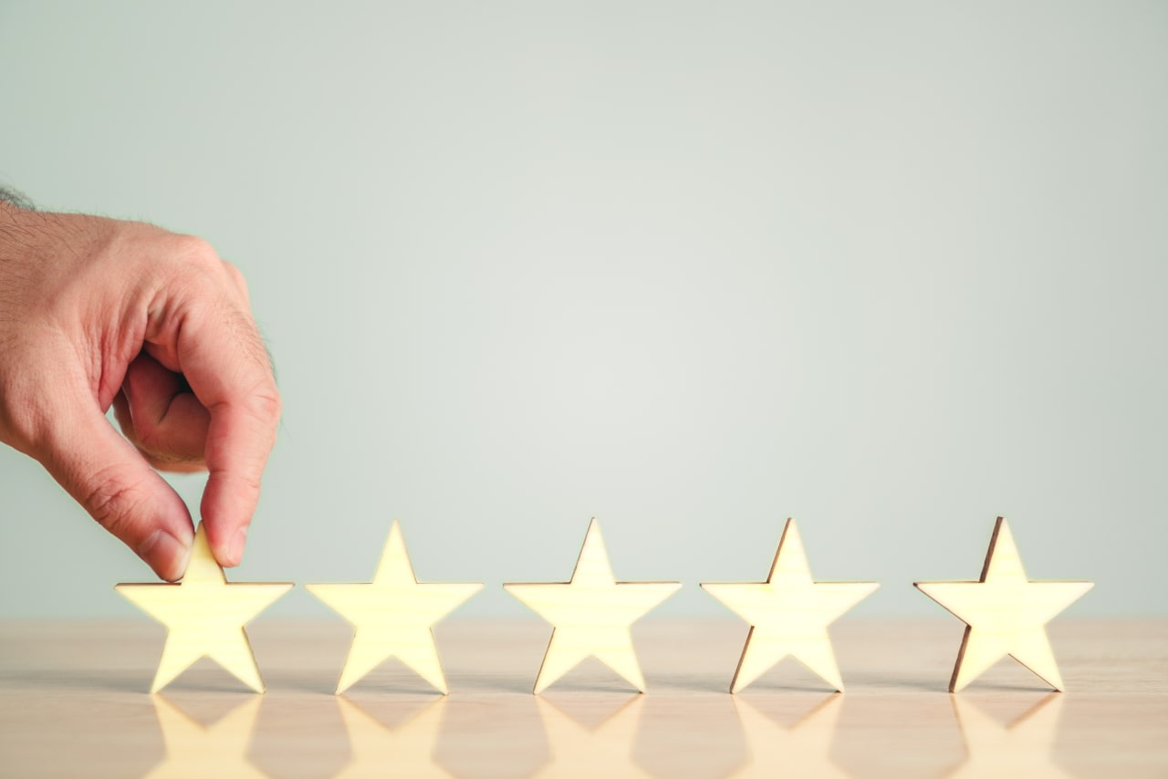 Hand picking up one star among five stars on table.