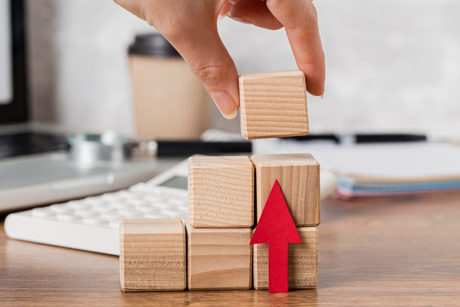 Hand placing wooden block to represent growth.