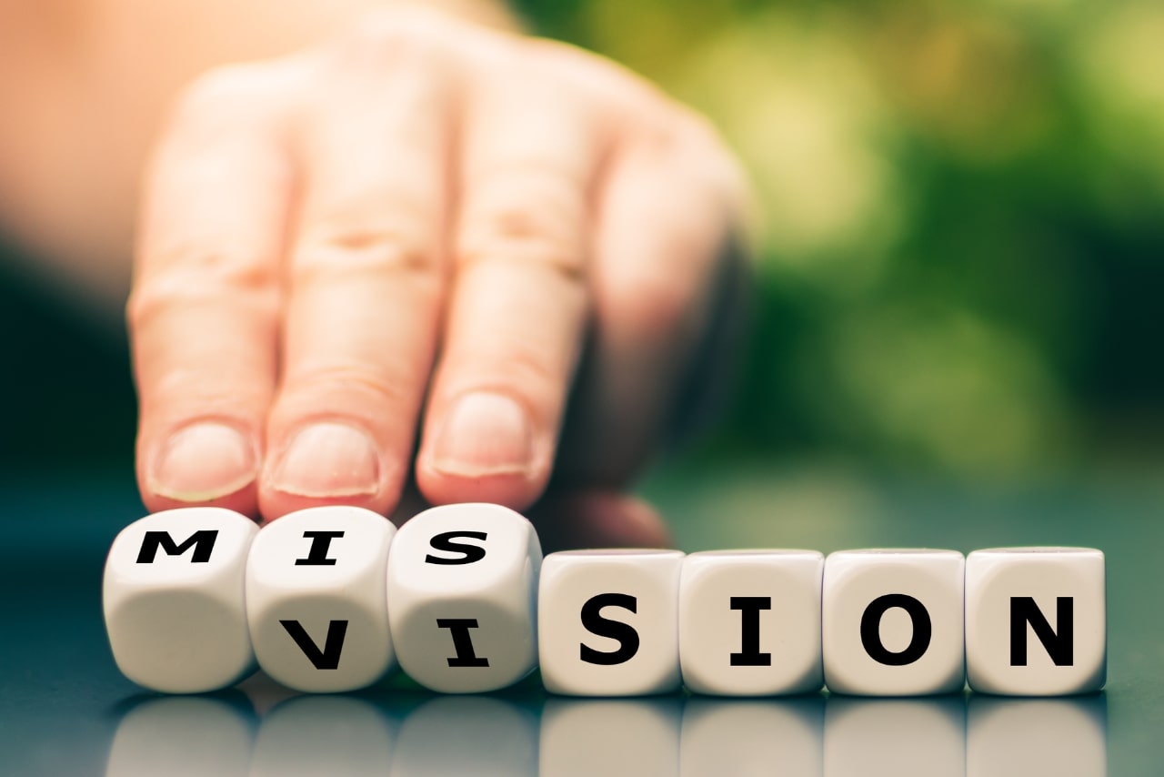 Hand turns dice and changes the word vision to mission.