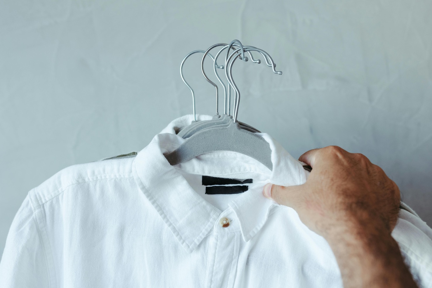 Hands holding couple of hangers with clothes.