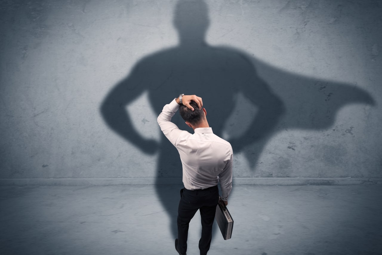 Hesitant businessman with superhero shadow.