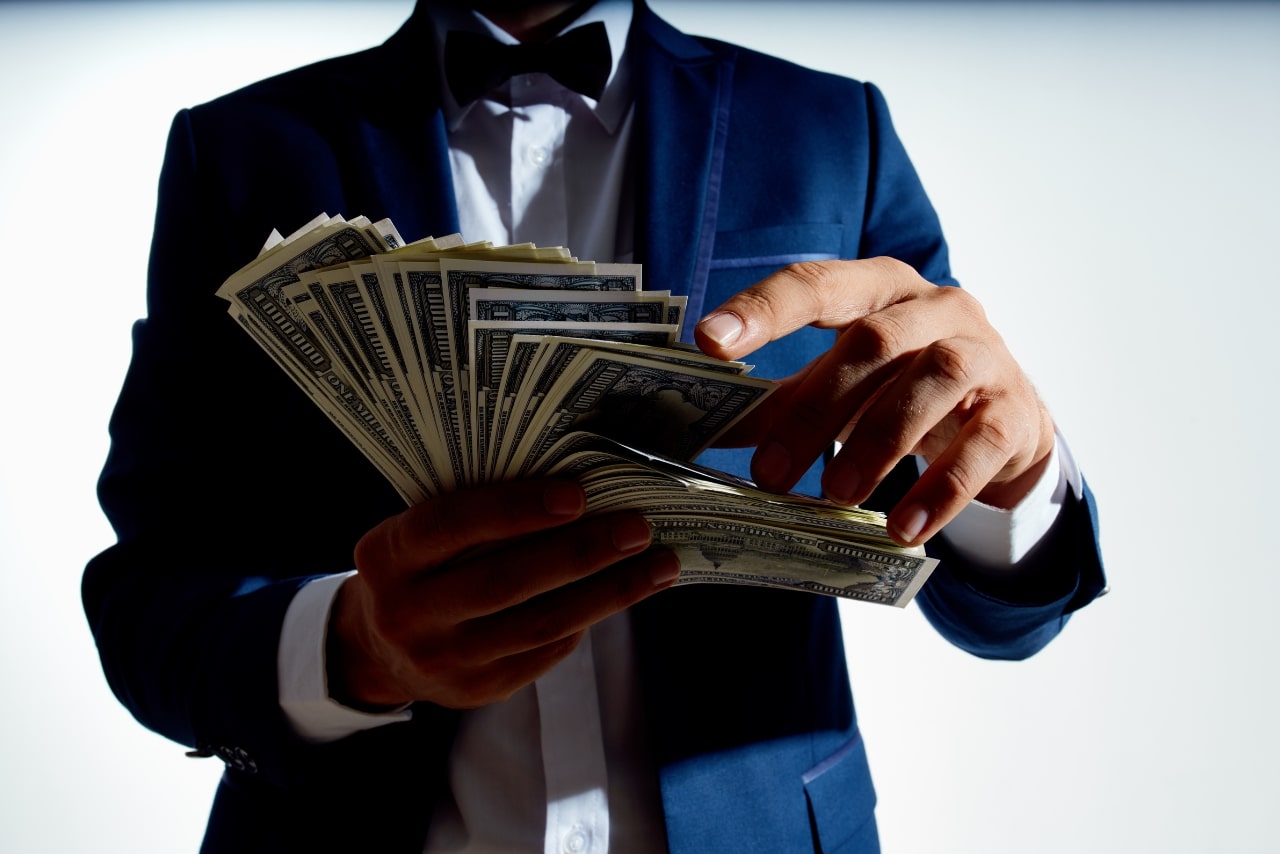 Millionaire businessman counting cash on hand.
