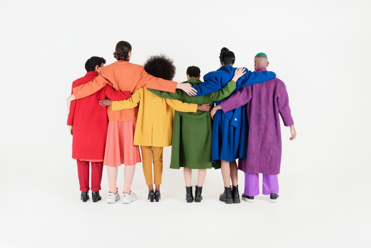 Non-Binary Friends in Colorful Outfits on White Background.