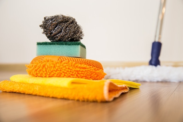 Orange rugs, scrubber and mop on floor.