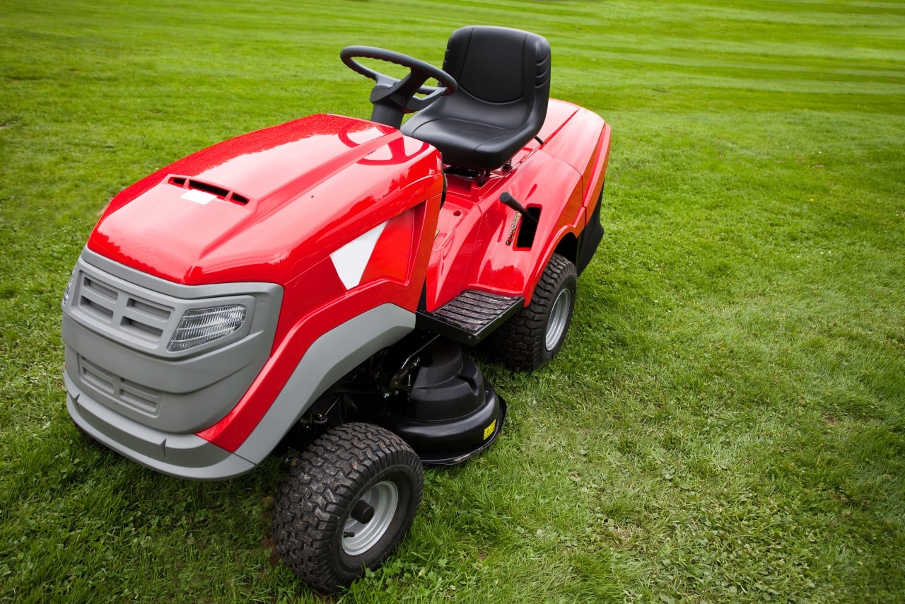 Red ride-on mower parked on the grass.