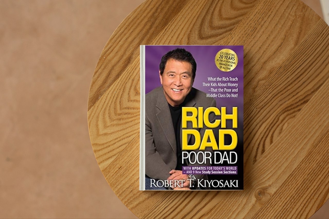 Rich Dad Poor Dad book on top of desk.