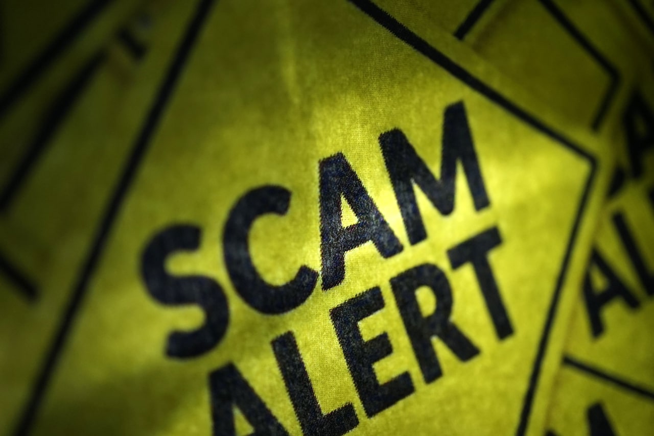 Scam alert yellow sign.