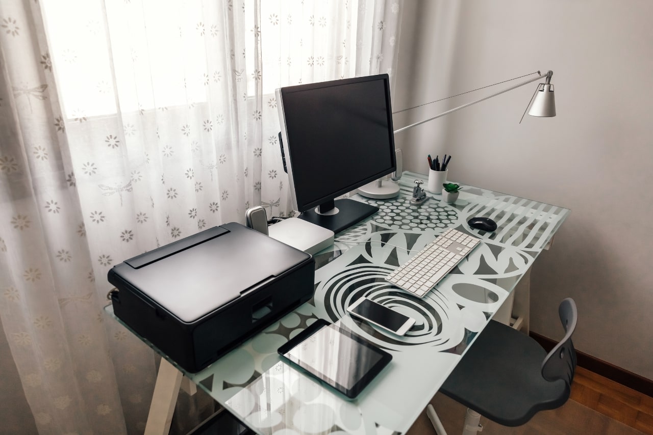Tidy workstation with table, chair and technological devices.