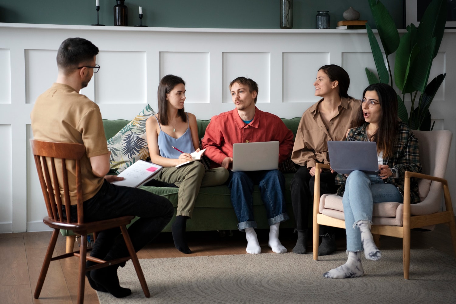 Two men and three women are having a conversation together in a room