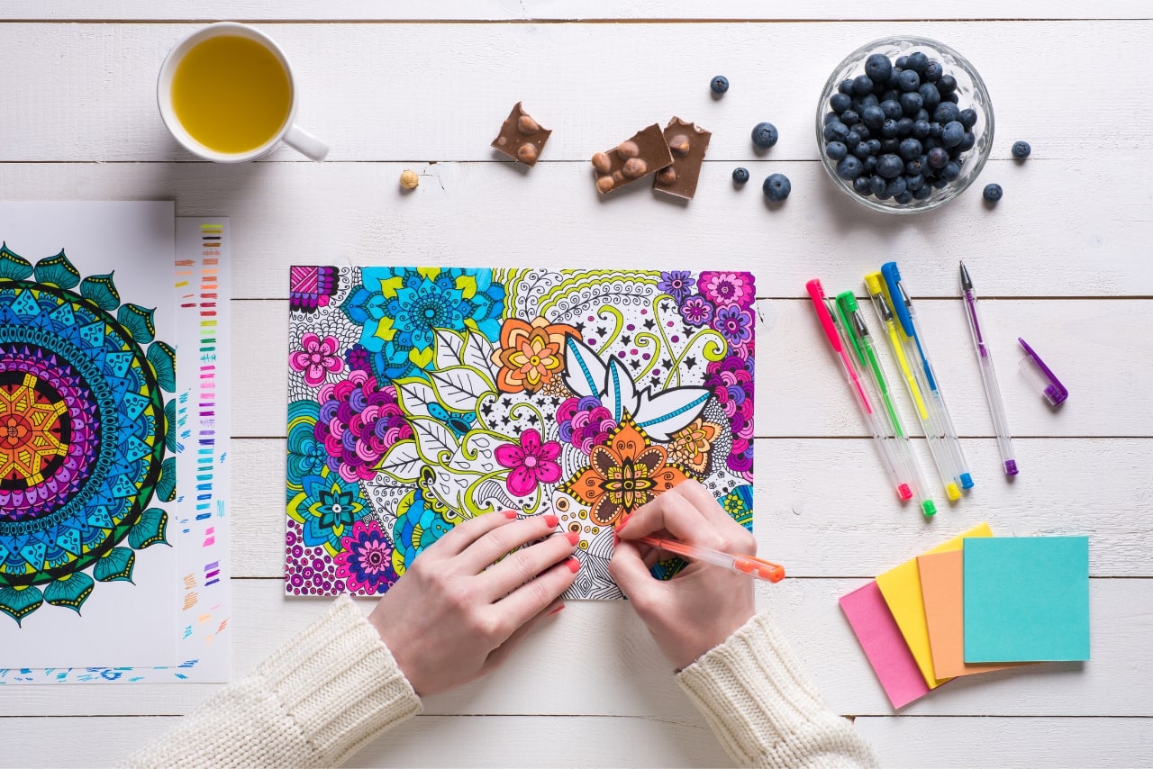 Woman coloring a printable page of a coloring book.