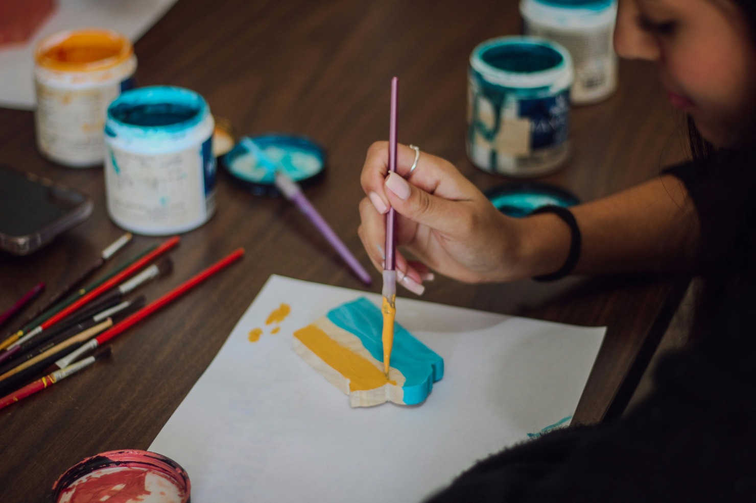 Woman painting a piece of woodcraft.