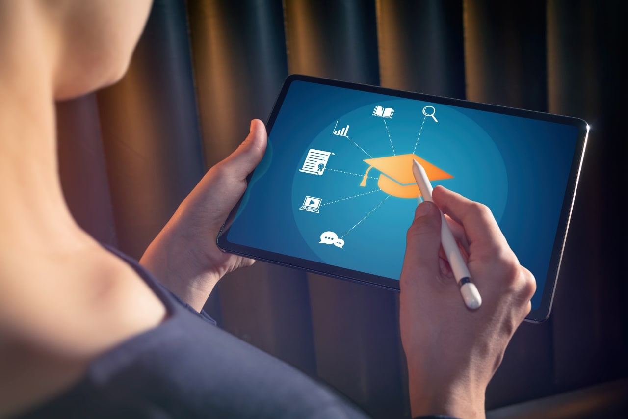 Woman selects graduation hat icon on her tablet.