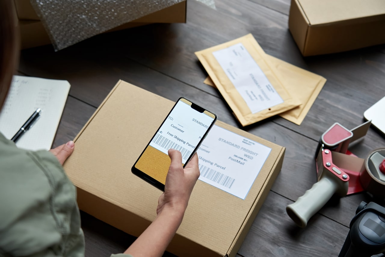 Woman taking a photo of her package's shipping details.