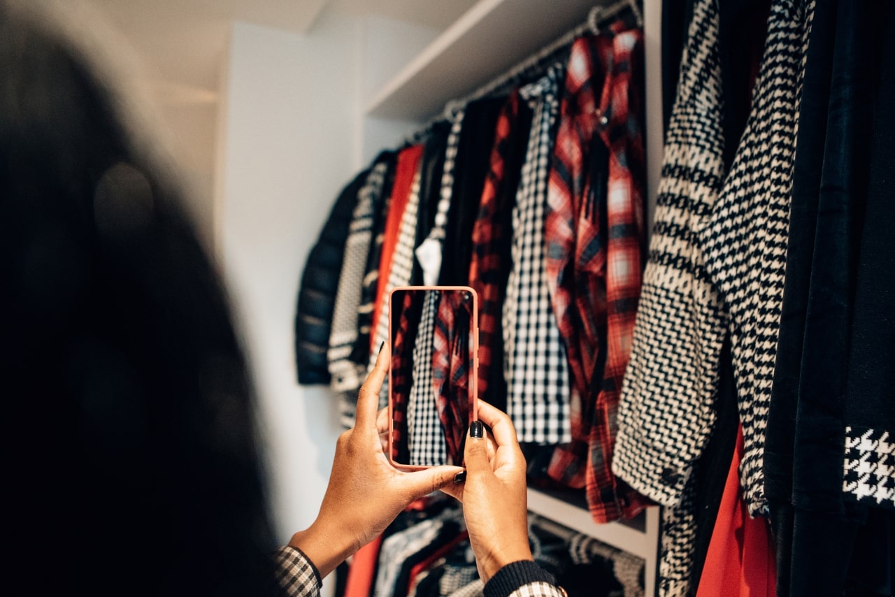Woman taking photos of clothes on her wardrobe.