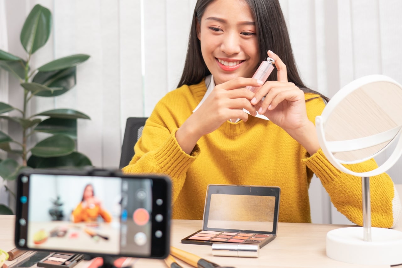 Woman using product while filming herself on phone.