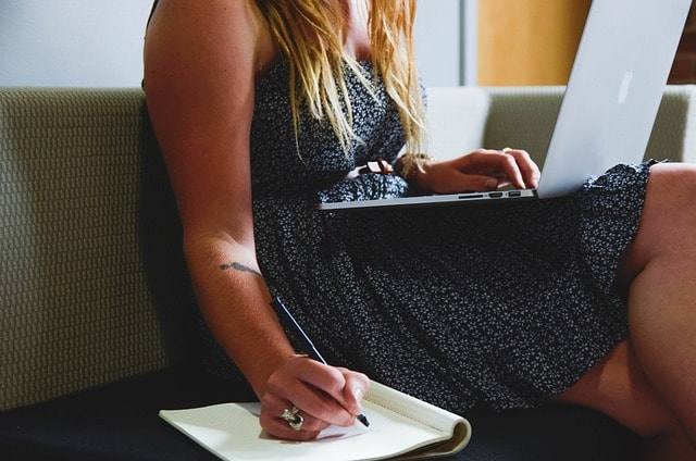 Woman writing and typing at the same time.
